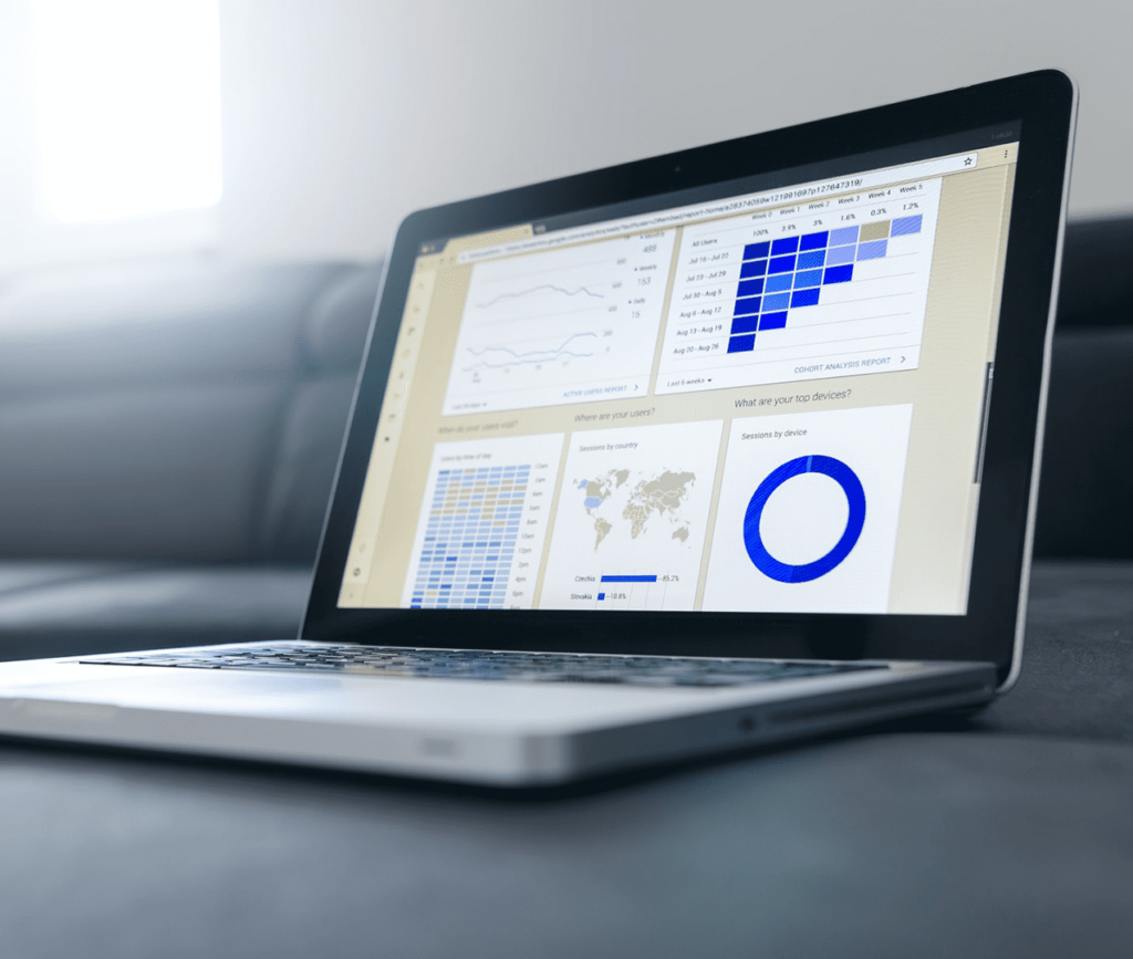 Laptop computer sitting on a couch with a dashboard showing all types of data metrics, KPIs and matrixes for post-market research