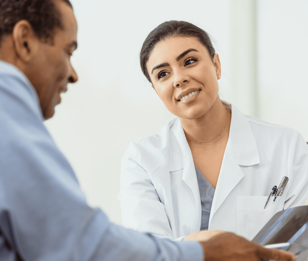 Female doctor listens to her patient as the man reviews documentation with her.