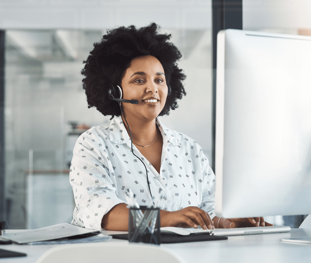 Woman works on her desktop at her desk with a headset on. Customer support representative.