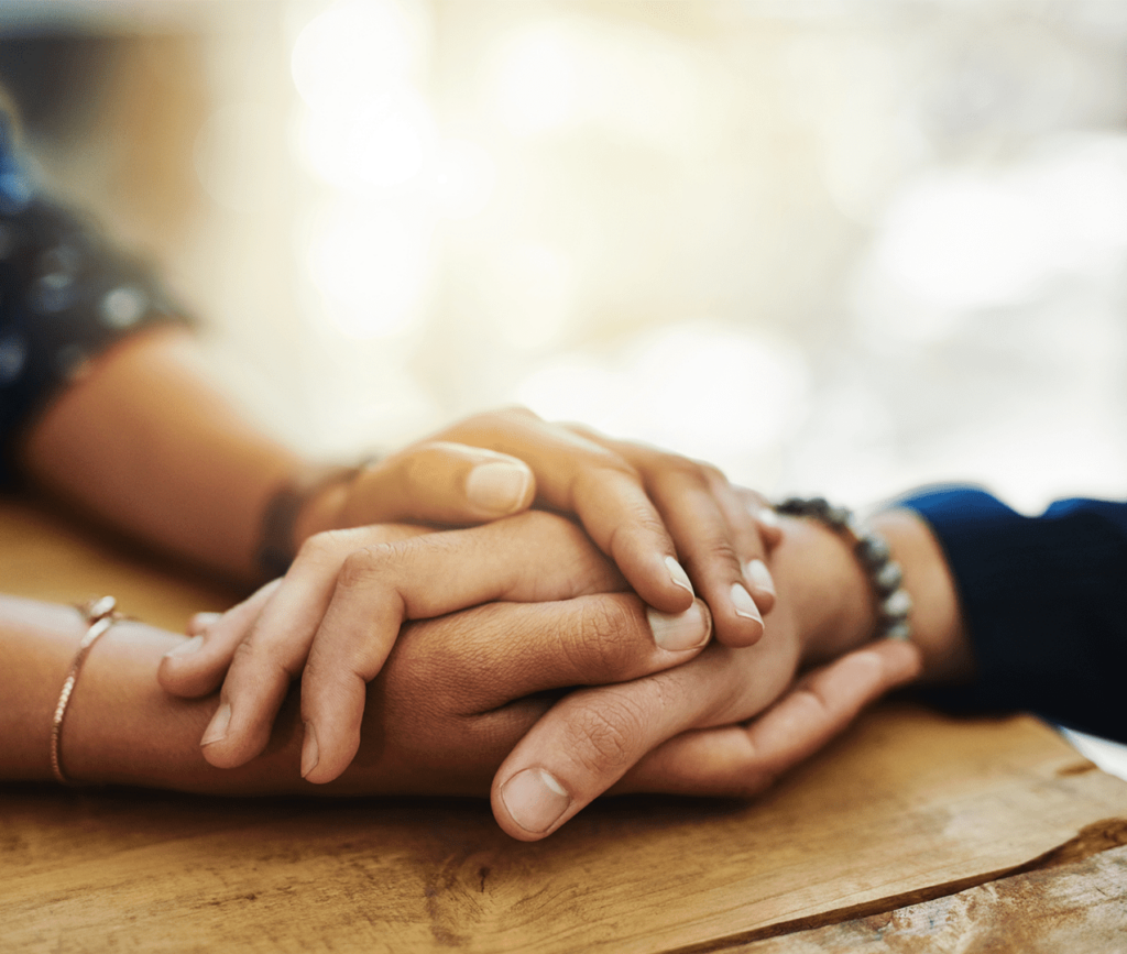 Close up of hand being compassionately embraced by a fellow woman.