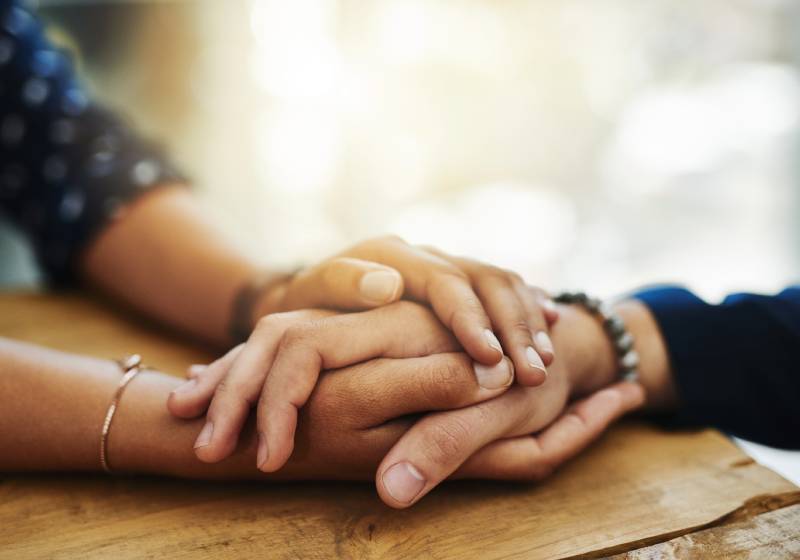 Close up of hand being compassionately embraced by a fellow woman.