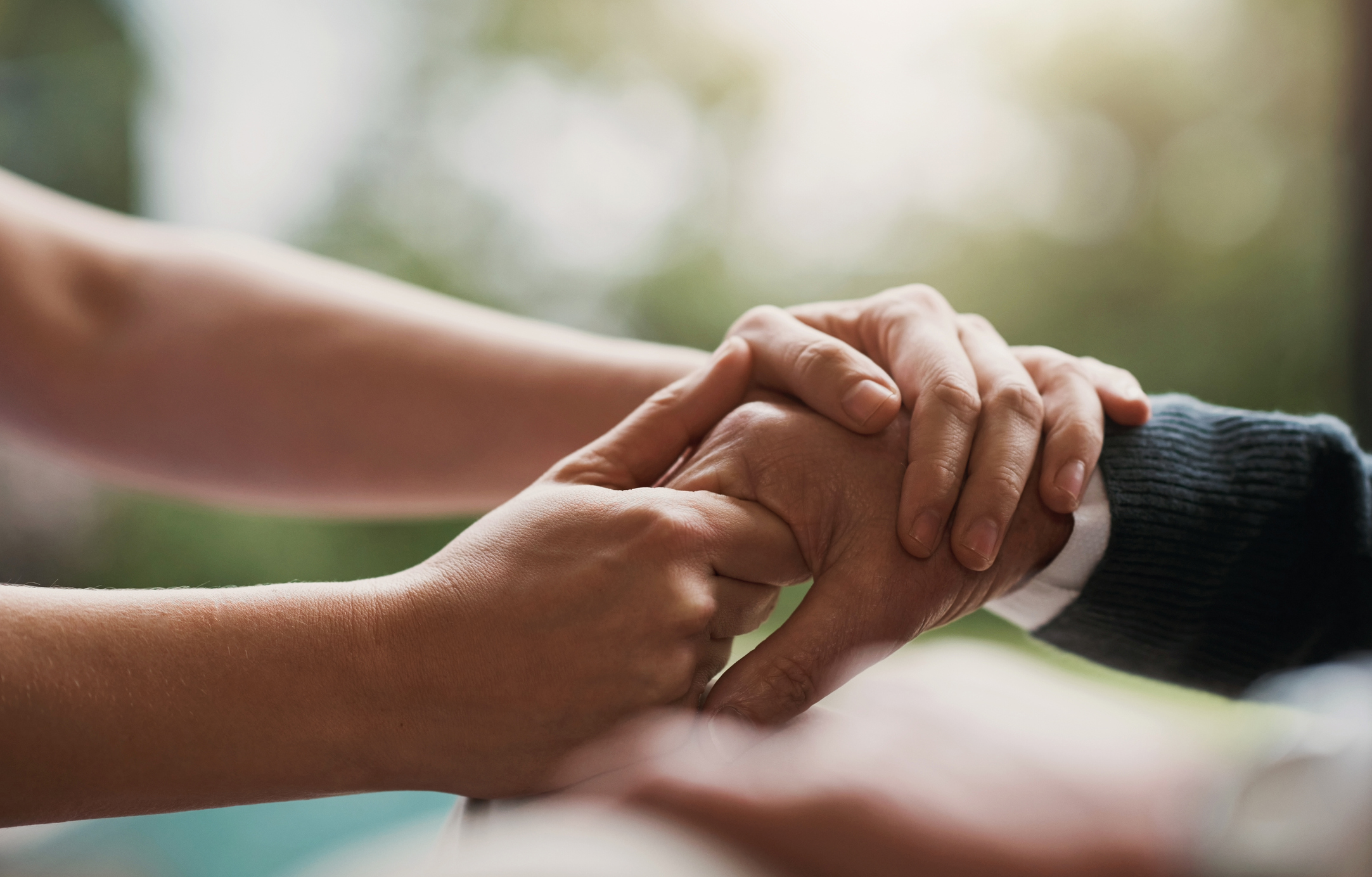 Closeup of two sets of hands holding each other, showing support.