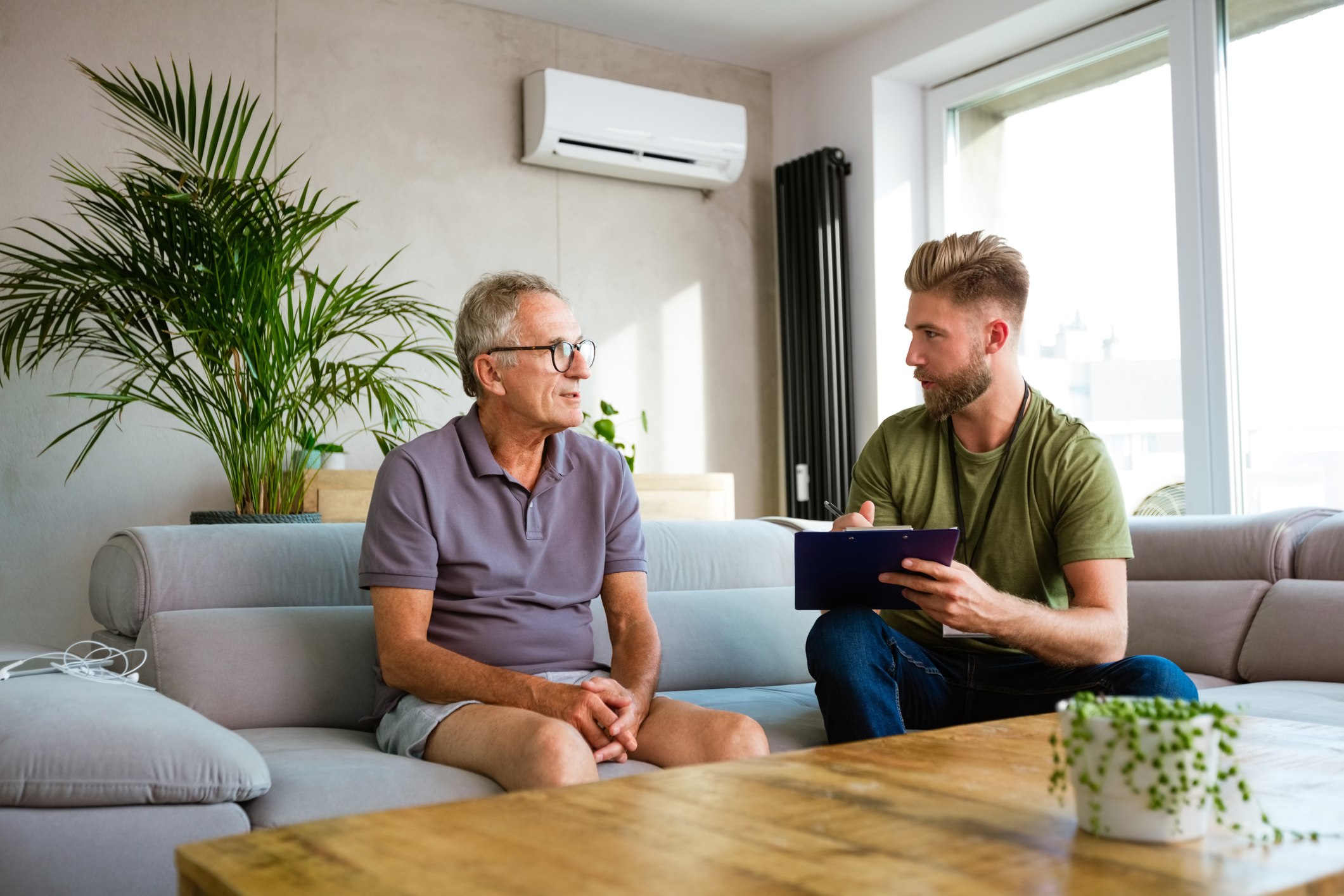 District nurse talking with senior man during home visit.