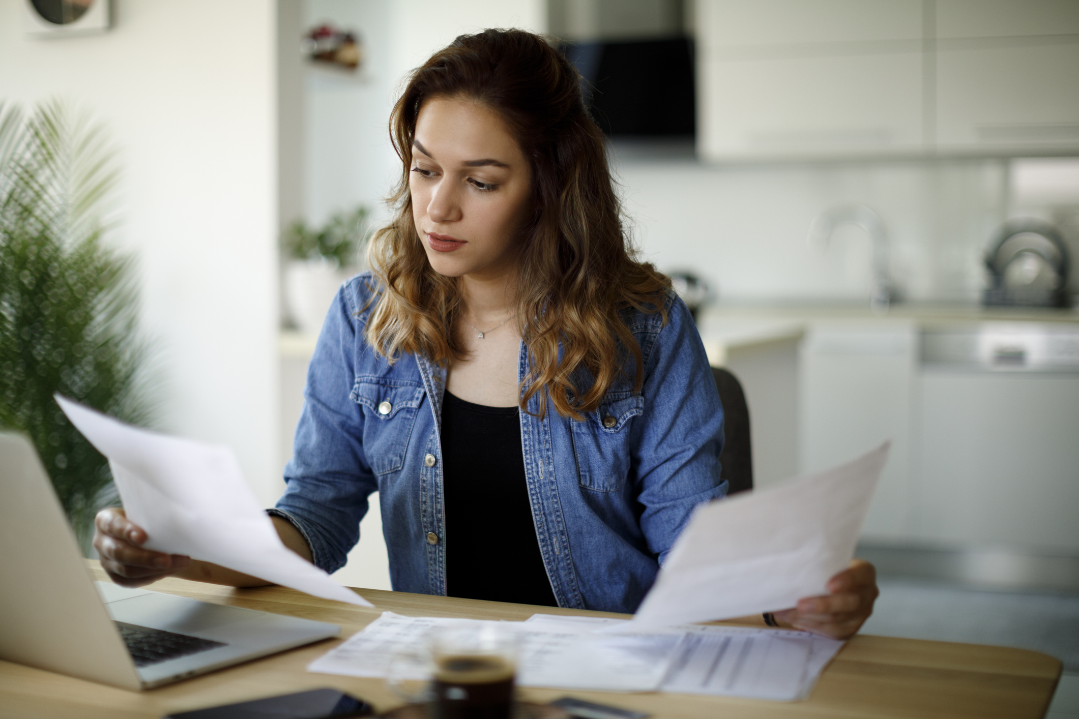 Serious young woman reviewing multiple documents in each of her hands.