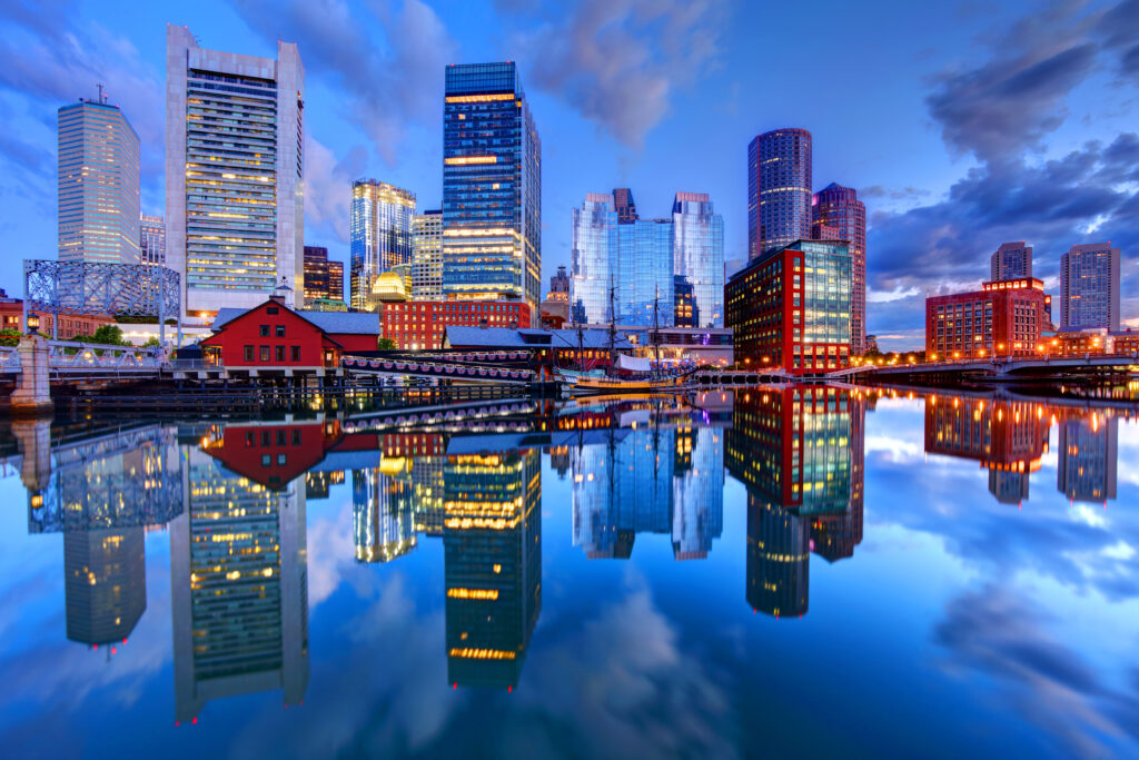 Boston, Massachusetts city skyline reflected in the calm water below.