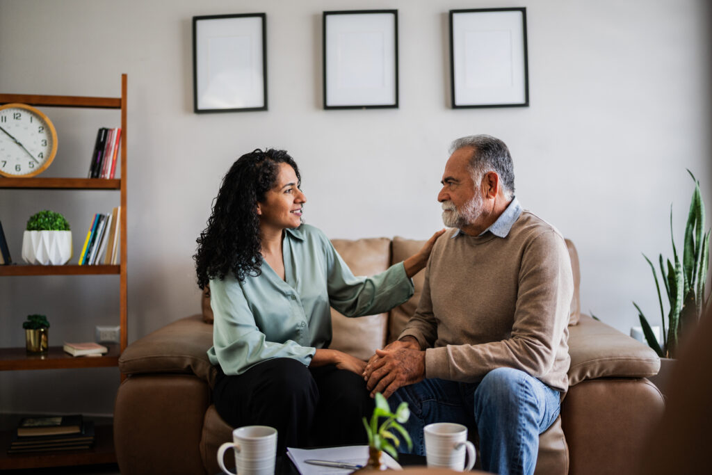 Middle-aged female therapists sits with a patient on the couch and comforts him, putting him at ease.