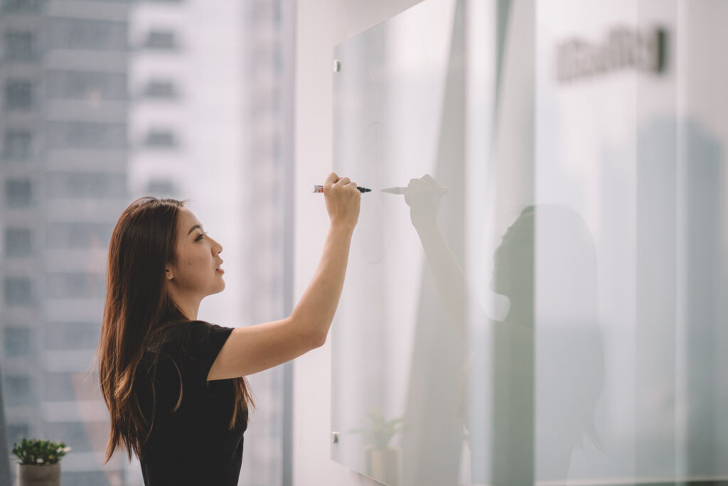 An Asian businesswoman writing on a whiteboard uring conference meeting